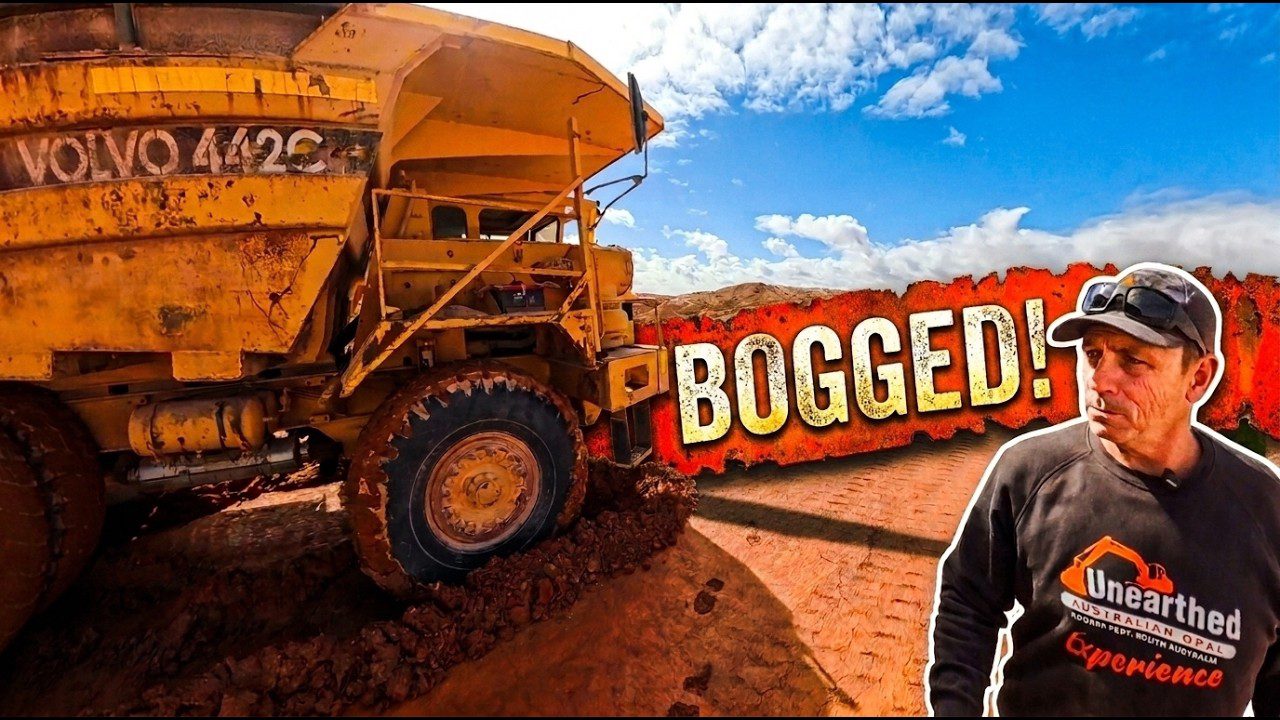 A yellow haul truck sunk into the mine road, with Dan beside it.